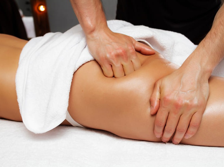 close nas mãos de esteticista realizando massagem detox nos glúteos de paciente